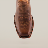 Close-up of the Azkar Tan - Wide Cutter Toe cowboy boot in rich cowhide leather, featuring intricate stitching on the square toe. Straight lines and decorative shapes enhance the detailed edge stitching, beautifully complementing its polished finish.