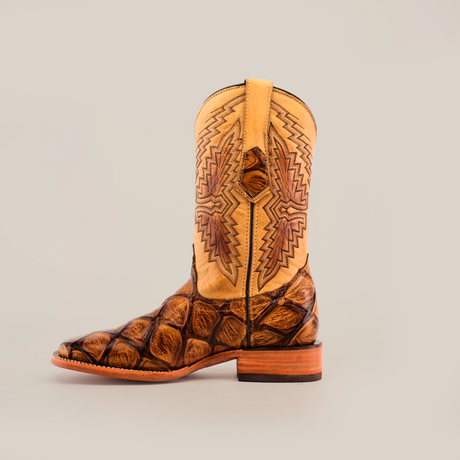 The Big Bass Pirarucu Print Orix - Square Toe is a cowboy boot featuring a tan and brown upper with intricate geometric stitching, a darker brown textured leather toe, and a wooden heel, all crafted from premium cowhide leather against a plain light background.