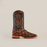 The Pirarucu Print Tan - Square Toe boot is crafted from premium cowhide, featuring intricate stitching and designs. It boasts a Pirarucu Print Tan finish on the lower section, a patterned smooth shaft, wooden heel, and a top pull strap.