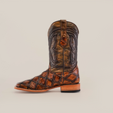 A single Pirarucu Print Tan - Square Toe cowboy boot, featuring a textured pattern and rich brown tones, stands upright. Made from premium cowhide, it showcases intricate stitching and a wooden heel, embodying a rustic yet stylish design against a light background.