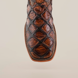 Close-up of the Pirarucu Print Tan - Square Toe artisan boot, crafted from premium cowhide with a textured diamond pattern in rich brown. Intricate edge stitching highlights its craftsmanship, set against a plain white background.