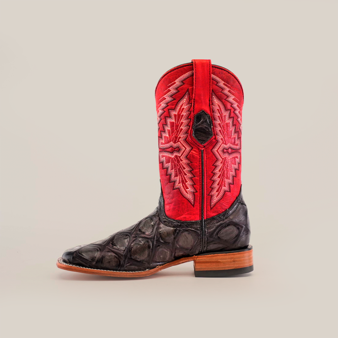 A single Big Bass Pirarucu Print Rustic Black cowboy boot showcases a black, textured leather foot and tall red shaft with intricate stitching. Made from premium cowhide leather, it features a classic square toe design and wooden heel, set against a light background.