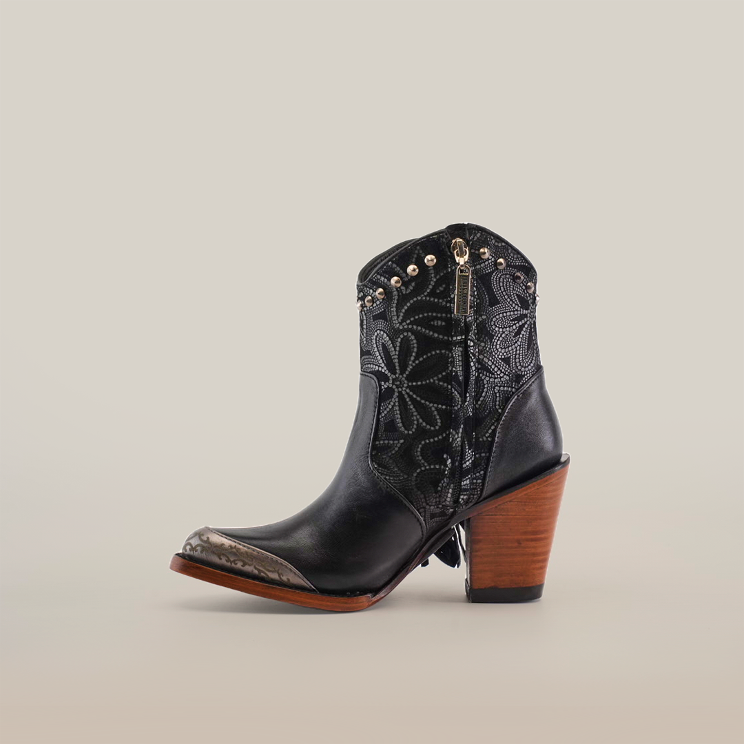 The Dallas Fringe Bootie Black - J Toe features premium leather, a single black cowboy boot with intricate patterns, a metal toe cap, and black leather fringes on the sides. It boasts a stylish brown wood heel against a plain white background—a true showcase of luxury craftsmanship.