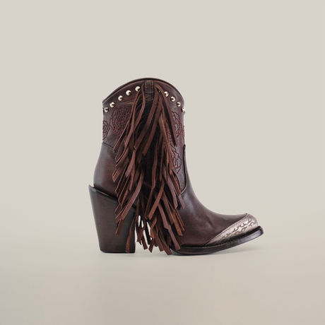 Introducing the Dallas Fringe Bootie Chocolate J Toe: a stylish cowboy boot with chocolate brown leather, high heel, side tassels, and metallic toe accents. Decorated with silver studs on top, set against a plain white background. Part of the Platinum Collection.