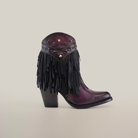 Introducing the Austin Fringe Bootie Wine - J Toe from the Platinum Collection: a purple and black leather masterpiece, adorned with metallic studs and fringe detailing. Its high heel and pointed toe, set against a plain white background, exude elegance.