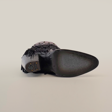 Bottom view of a wine-colored Austin Fringe Bootie with a J toe, showcasing a worn sole with patterns. The heel has an emblem, and the premium leather features fringe details. The photo is set against a plain white background.