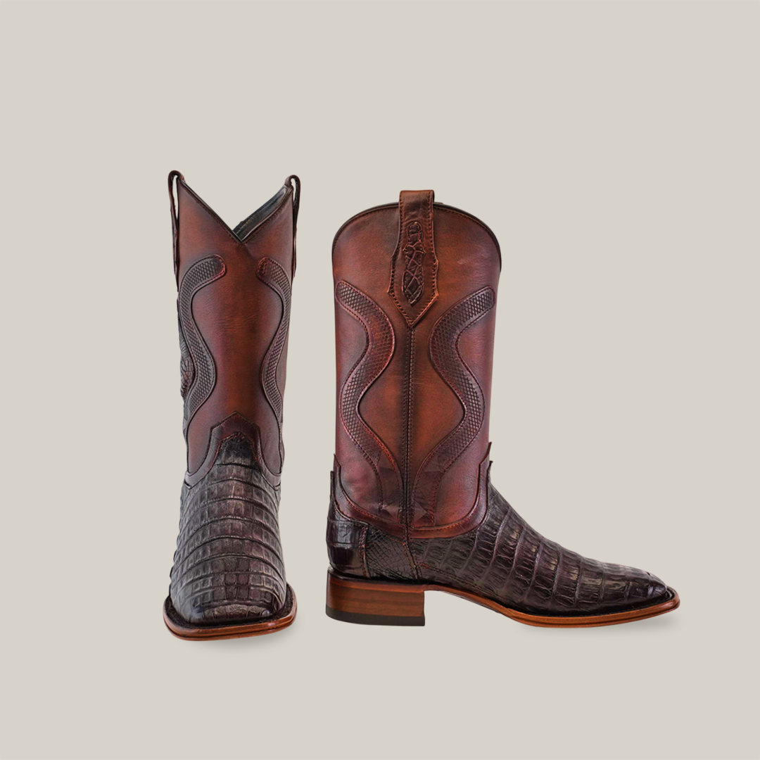 The Exotic Caiman Belly Tail - Diamond - Tabaco - Square Toe brown cowboy boots feature textured caiman leather and intricate stitching. One stands upright, the other is turned to display its side, set against a plain backdrop—ideal for Western fashion lovers in the Platinum Collection.