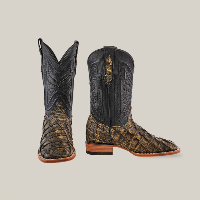 The Exotic Piraruco Fish boots are crafted with dark reptile-patterned leather on the lower half and black leather intricately stitched on the upper shaft, featuring wooden heels and a square toe design, set against a plain background.