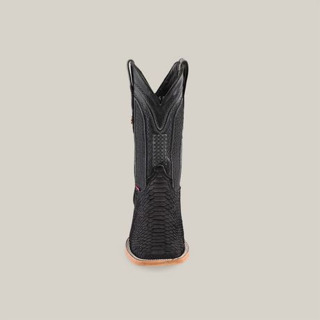 A single Exotic Python boot in matte black with a square toe is shown from the back, showcasing its exotic texture. Detailed stitching decorates the shaft, complemented by a tan sole, all set against a plain beige background.