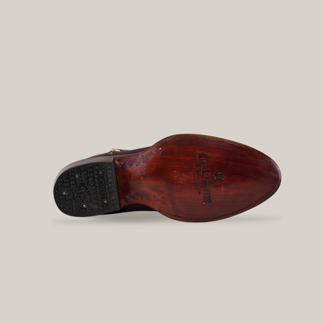 The image showcases the underside of a single Exotic Stingray dress shoe in brown leather, featuring a polished wooden sole with visible branding and nails, reminiscent of an exotic stingray boot, while the black heel offers extra grip.