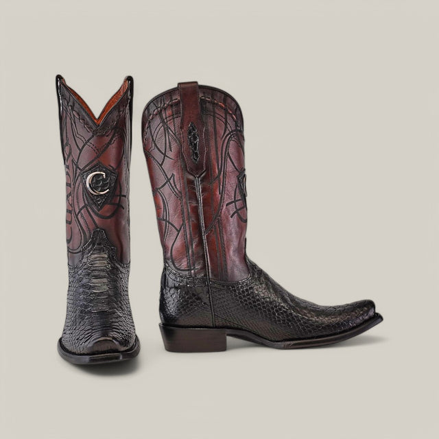 The Cuadra Plunge Black Python Laser & Embroidery boots, featuring intricate stitching and a textured design, showcase one upright boot and another in profile on a gray background. These narrow square-toe masterpieces could be enhanced with exquisite laser engraving for added allure.