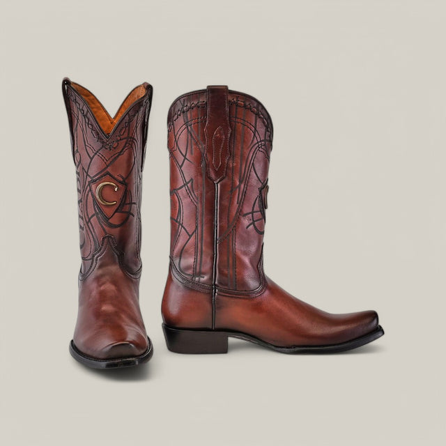 The Cuadra Over Chestnut Laser & Embroidery boots (CU347) showcase their intricate stitched design, with one boot forward and the other sideways, highlighting the narrow square toe and square heel against a plain background.