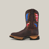 The Taurus Moka Composite Toe - E6189 boot is a brown leather cowboy style featuring decorative American flag patches on the shaft. It has a durable black sole with tan accents, perfect for any adventure or work setting.