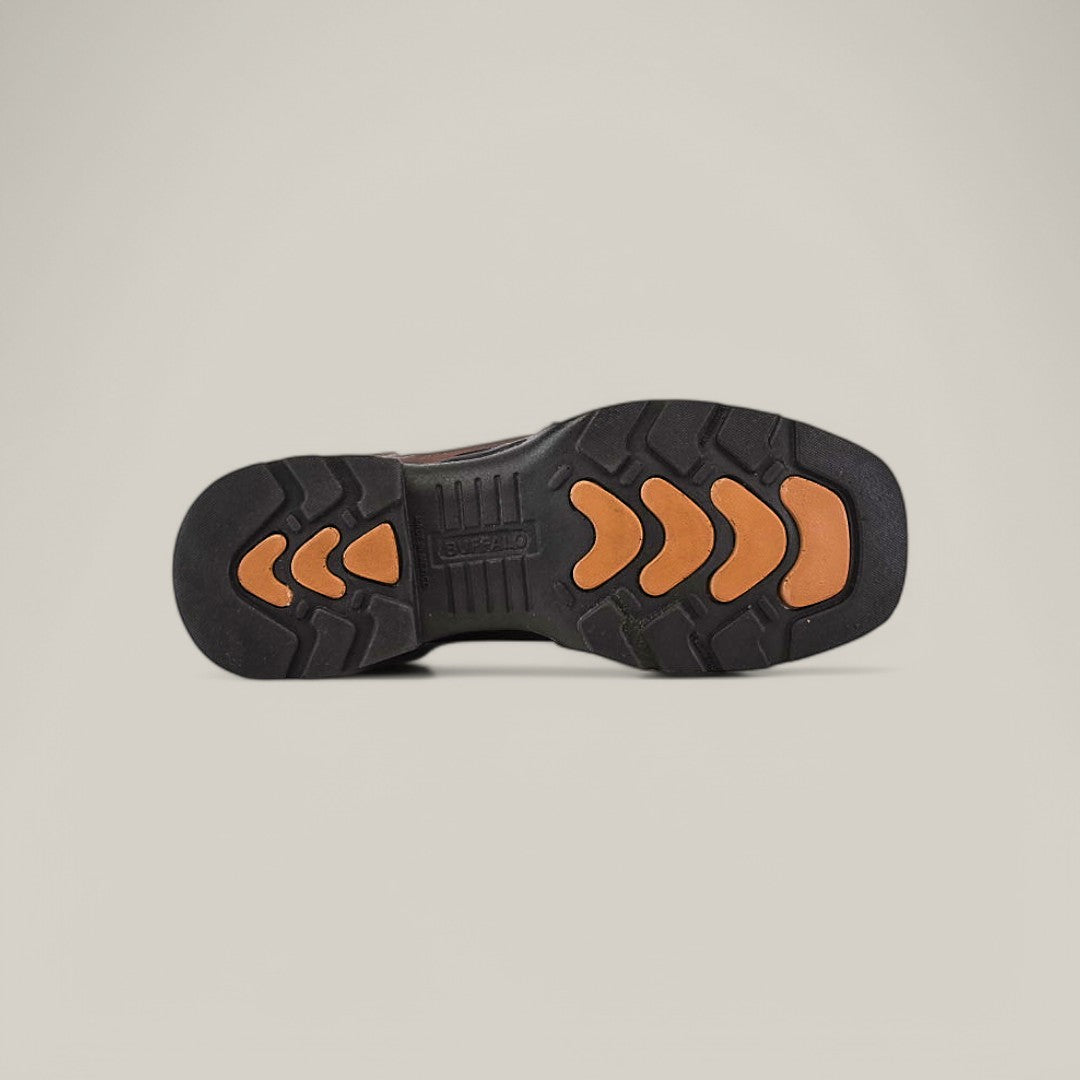 The image shows the sole of the Taurus Moka Composite Toe - E6189 shoe, featuring a black base with brown arrow-shaped treads, enhancing grip and durability. The branding is centered on a light gray background.