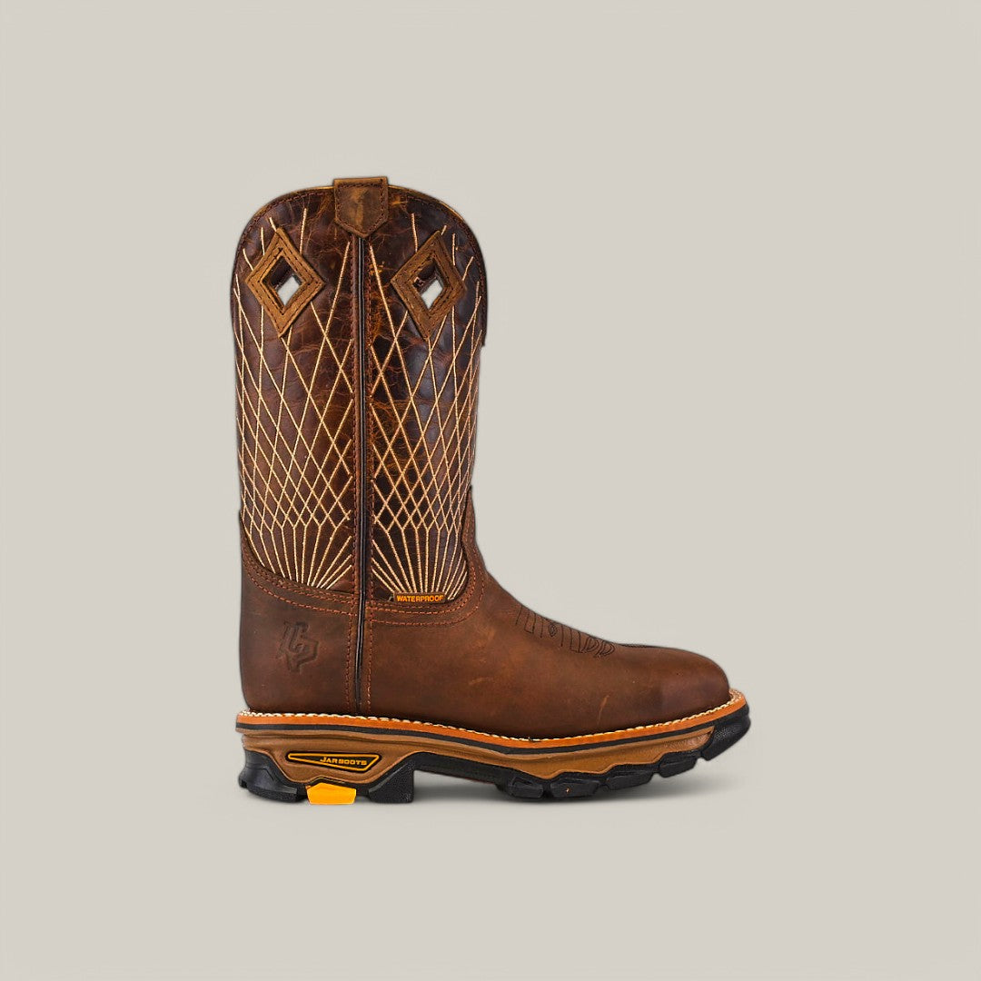 The Amazonas Tanger Soft Toe - E6257 features one brown cowboy boot with intricate stitching and diamond-shaped cutouts on the shaft. It exudes rugged durability with its textured sole accented in orange, showcased from the side against a plain gray background.