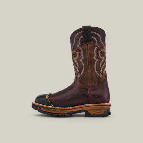 The Amazonas Chocolate Composite Toe - E6258 showcases Texas Country Work Boots rugged charm with a brown cowboy boot featuring intricate white stitching, brown leather accents, and a black toe cap. Its durable sole has a raised heel and textured grip, all set against a plain light beige background.