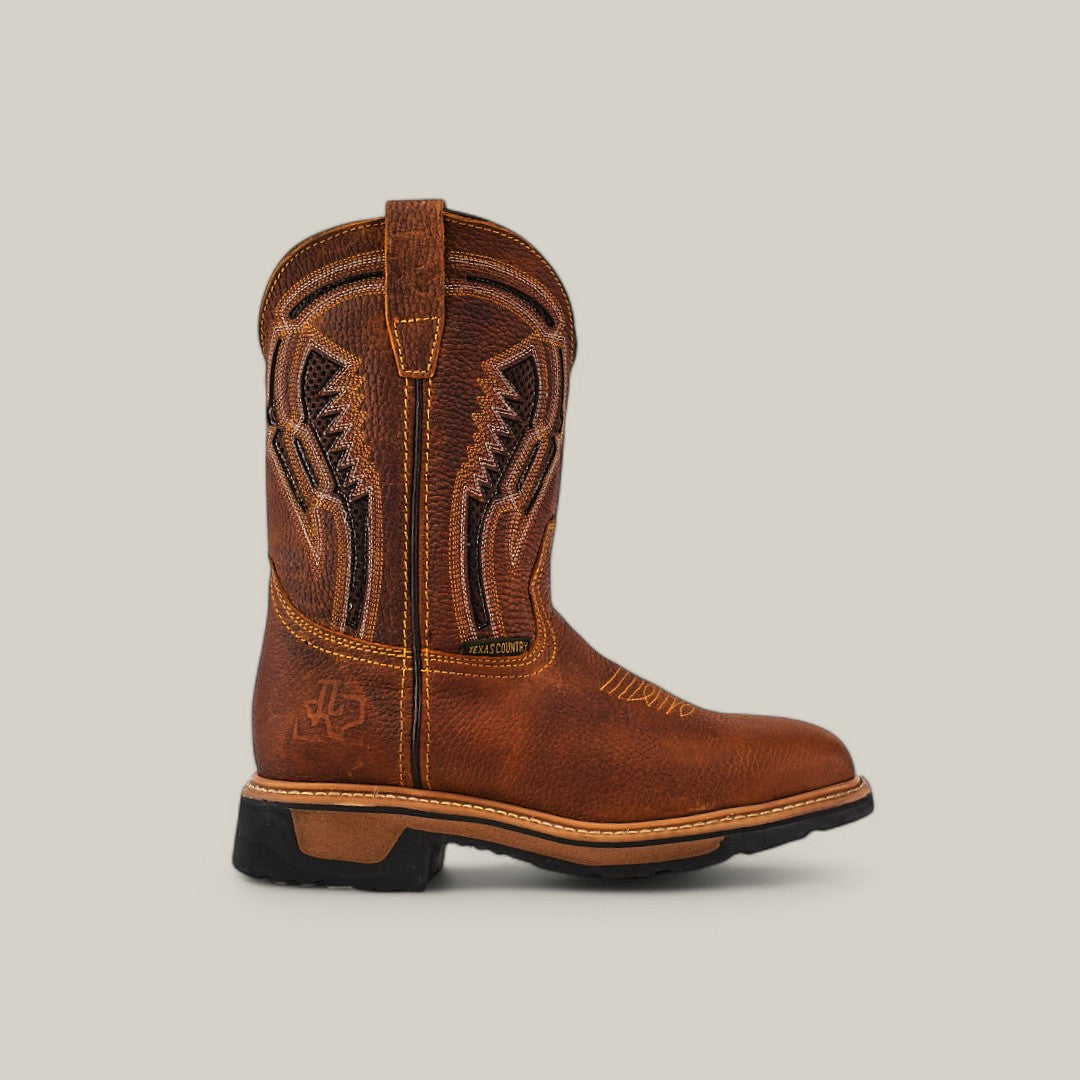 The Floter Honey Composite Toe - E6987 Work Boot features a brown leather design with detailed shaft stitching and decorative curves. It has a black sole, low heel, and pull tabs for easy wearing, all set against a solid light gray background to highlight its rugged charm.