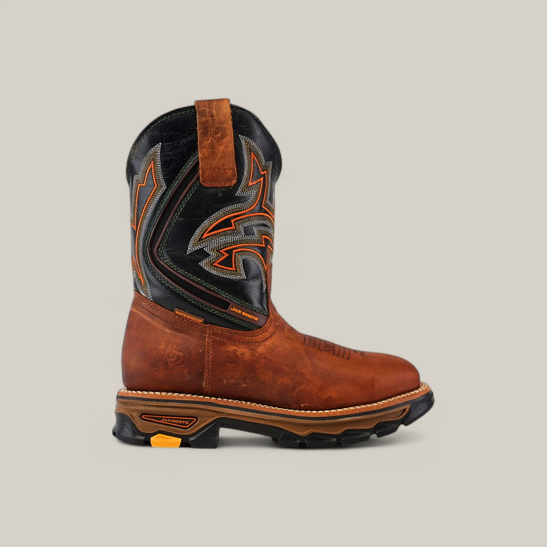 The Amazonas Honey Composite Toe - E6002 is a durable brown and black work boot with an orange and black intricate stitched design on the shaft. It features a textured grip sole for rugged adventures, all set against a plain beige background.