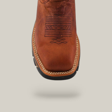 Close-up of the durable Amazonas Honey Soft Toe - E6002 boot in brown leather with decorative black stitching on the toe. It features a square toe design and prominent stitching along the sole edge, set against a plain light background.