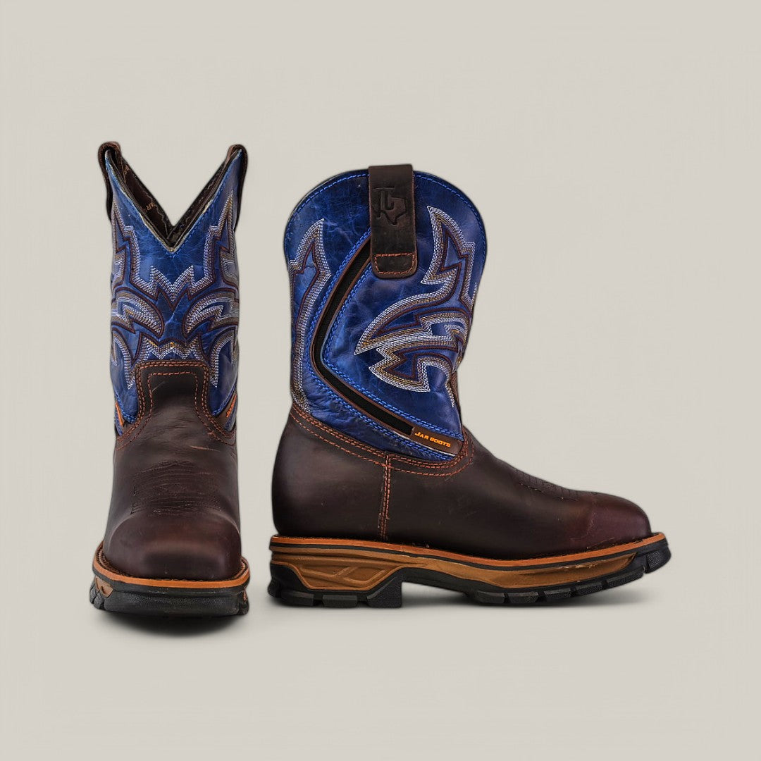 The Amazonas Brown Composite Toe - E6002 boots display durability with brown leather feet and blue shafts, intricately stitched. One boot faces forward and the other sideways, set against a light gray background, emphasizing their cowboy elegance.