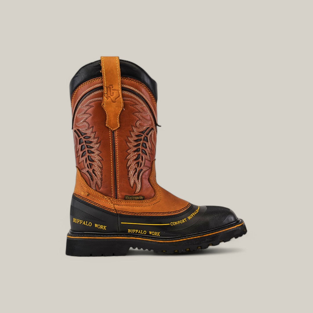 The Crazy Honey Composite Toe - E6048 is a brown and black leather cowboy boot with intricate stitching, decorative patterns, and a rugged sole labeled BUFFALO WORK. Renowned for its durability, it features a pull tab at the top against a solid light gray background.