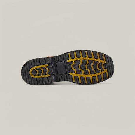 The image highlights the sole of the Crazy Honey Soft Toe - E6048 boot, featuring black and yellow tread with zigzag and straight lines for optimal grip. A plain, light gray background accentuates its durability and robust construction.