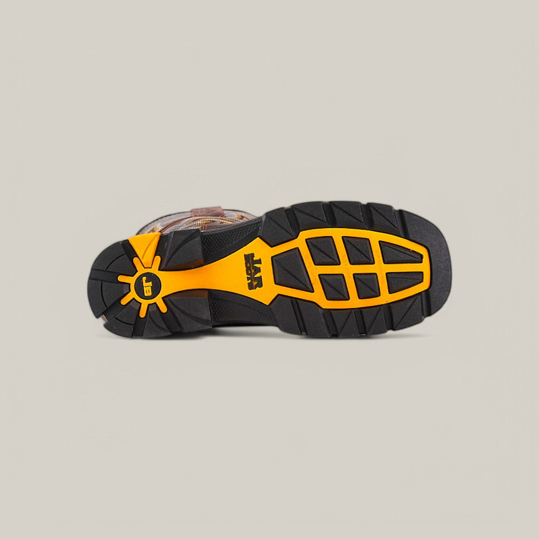 The image displays the sole of the Amazonas Chocolate Composite Toe - E6002, featuring a black and yellow tread pattern for superior grip and durability. A logo is visible near the heel against a plain, light background, evoking rugged Texas Country Work Boots.