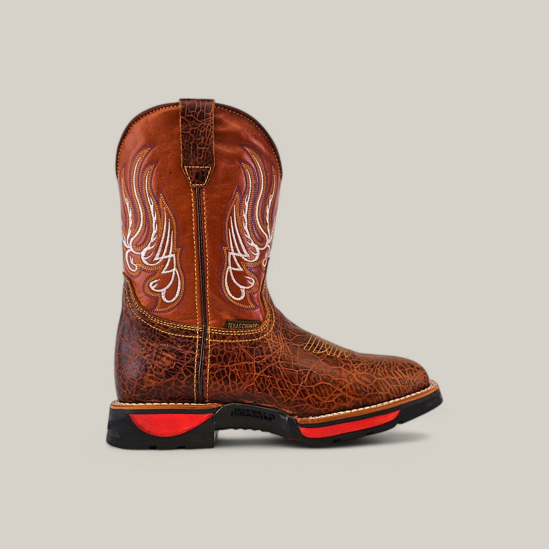 The Jurasic Honey Soft Toe - E6080 is a single brown cowboy boot with intricate wing-like white stitching, featuring a textured leather finish, black sole with red accents, and a pull tab. Its ideal for durability in all conditions against a neutral background.