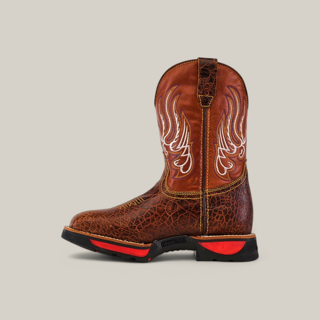 The Jurasic Honey Composite Toe - E6080 is a brown cowboy boot featuring intricate white stitching on the shaft, a textured leather finish, and a sturdy sole with black and red accents, all against a plain light grey background.