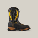 Against a plain beige backdrop, the Rhino Black Composite Toe - E6087 cowboy boot features yellow lightning bolt accents and orange stitching. Celebrated for its durability and comfort, it showcases a rugged sole and has a convenient pull-tab at the top.