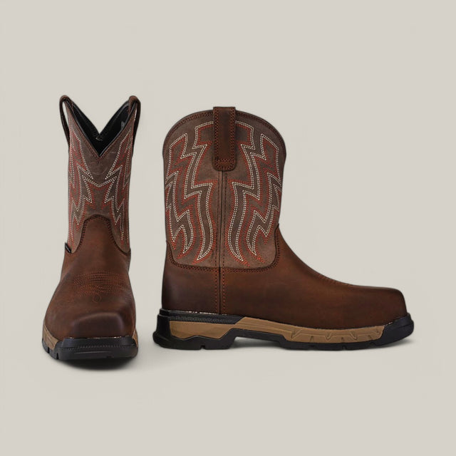 The Rebar Flex Western Brown boots (Composite Toe - 10053616) feature decorative stitching, one standing upright to show the front and the other tilted to reveal intricate leather patterns on the side. They combine style with rugged durability through Ariats Rebar Flex technology and a dark rubber sole.