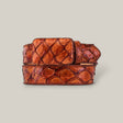 The Exotic Full Quilt Pirarucu Fish - Brandy Belt features a coiled, textured design with a rich, reddish-brown shade and distinct scaly pattern reminiscent of reptile skin, set against a plain light gray background.