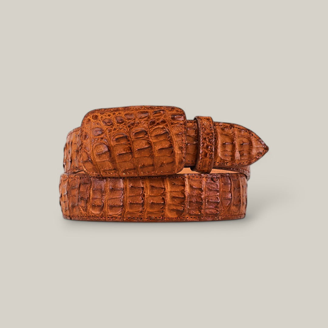 The Exotic Full Quilt Caiman - Honey belt features a rich brown leather with an eye-catching full quilt caiman texture. Its gleaming buckle sits prominently against a light background, enhancing its luxurious appeal.