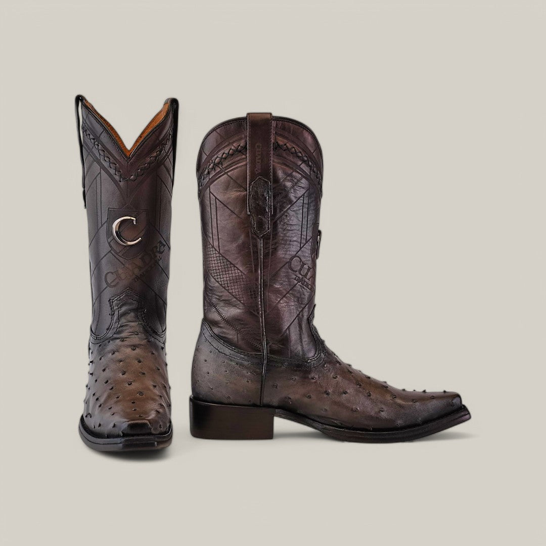 A pair of Everest Gray Ostrich Laser & Woven Cowboy Boots with narrow square toes are set against a plain background. They showcase ornate stitching and a star emblem on the side, with one boot upright and the other lying down.