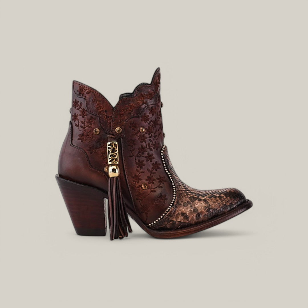 Introducing the Ximena Bootie - Python Choco - Round Toe from the Platinum Collection, featuring a brown cowboy ankle boot with decorative embroidery, patterned toe, carved heel, tassel detail, and metal accents on a neutral background.