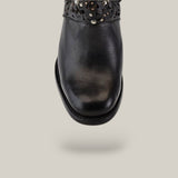 A close-up showcases the CU439 Black Laser & Crystals Round Toe Boot adorned with decorative floral and stud accents, sparkling with crystals. The black leather boot is elegantly positioned against a light gray background.