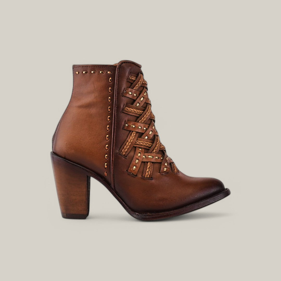 The Toledo Chestnut Laser & Woven - Round Toe (CU573) ankle boot in brown leather showcases decorative laces and stud details. Set against a plain light background, it embodies the timeless elegance of Cuadras craftsmanship.