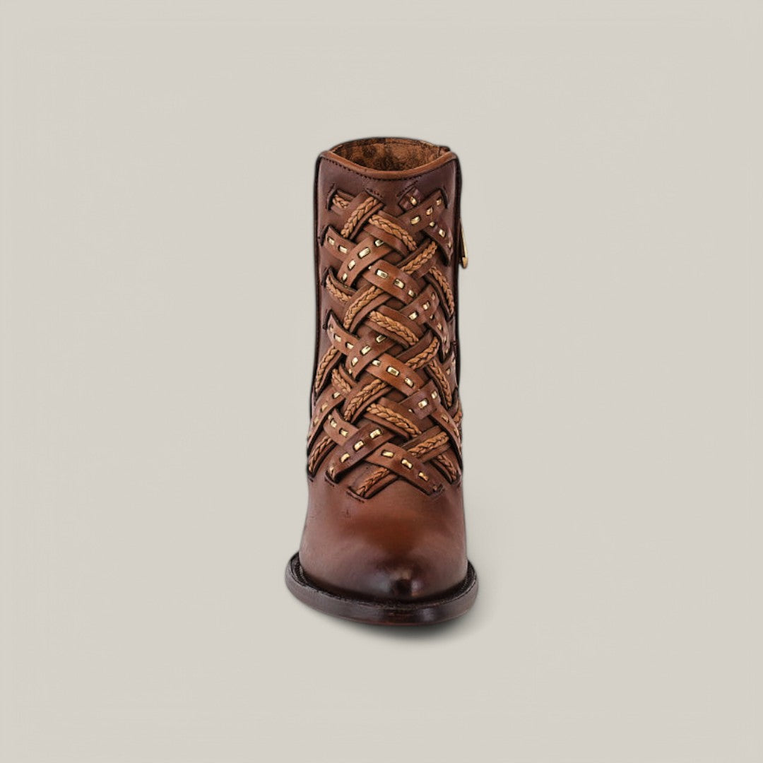 The Toledo Chestnut Laser & Woven (CU573) features a front view of a brown leather ankle boot with intricate woven detailing, lighter brown strips, and metal studs. It showcases a smooth round toe and short sturdy heel against a light gray background.