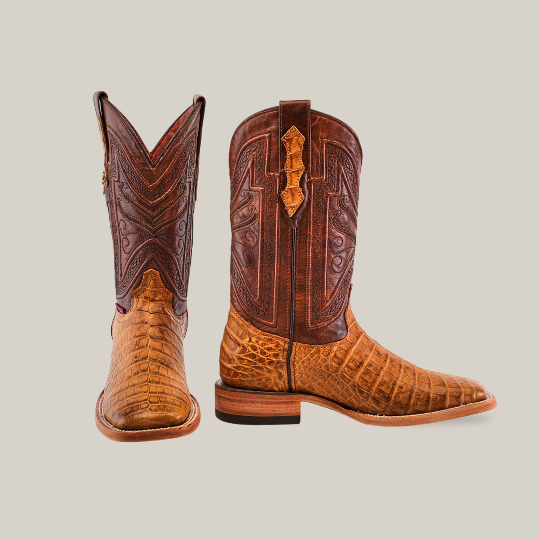 A pair of Exotic Caiman Horn Back boots in rich brown leather, featuring square toes and intricate stitching patterns with a texture resembling alligator skin. One boot stands upright while the other lies on its side against a plain background.