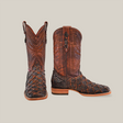 The Exotic Piraruco Fish Square Toe boots in rustic cognac showcase intricate stitching and leather patterns. The left boot stands upright, and the right reveals its textured finish, highlighting handcrafted quality with Piraruco fish leather accents.