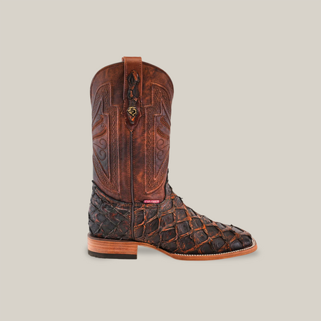 The Exotic Piraruco Fish - Rustic Cogñac - Square Toe boot flaunts a stylish dark brown upper with intricate designs, a textured lighter brown lower, and decorative stitching. Handcrafted with Piraruco leather, it features a pull tab and comes in a stunning rustic cognac finish.