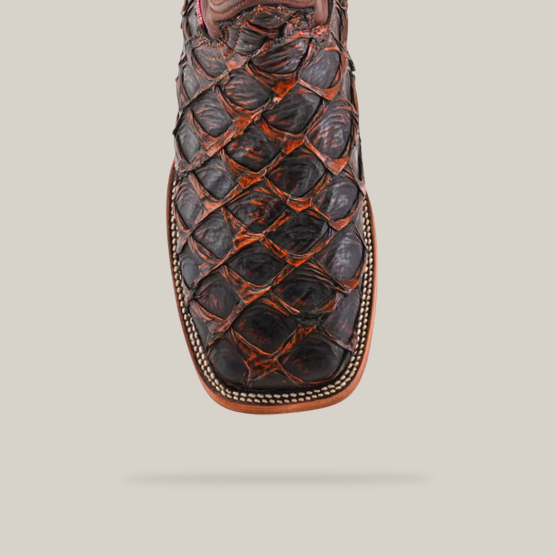 Close-up of the Exotic Piraruco Fish boot in Rustic Cogñac, showcasing large dark brown scales, a squared toe, and detailed stitching on a plain, light background.