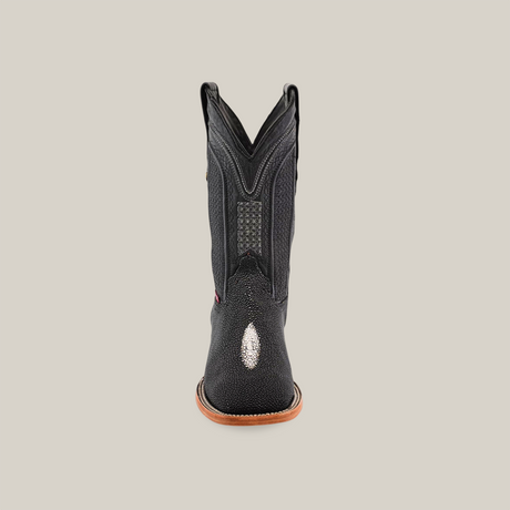 A black Exotic Stingray cowboy boot with intricate stitching is shown from the front on a neutral background. Featuring Western luxury, the boot flaunts a distinctive exotic stingray finish and square toe, alongside a tan sole.