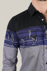 A person wears the Modern Fit Cotton Stretch Rodeo Panoramic Print Shirt (AZL9941) by Platini, featuring black and blue stripes with cactus and cowboy illustrations. It has snap buttons, a black collar, and is visible only from the upper body against a plain backdrop.