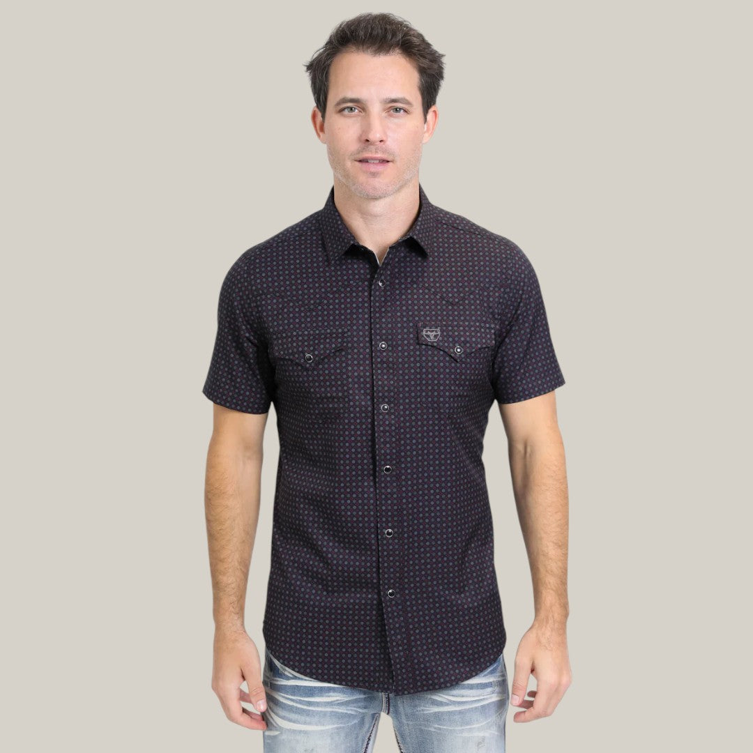 A man with short dark hair confidently poses against a light background wearing the Mens Performance Western Short Sleeve Aztec Print Black Shirt - PGW10639 and light-wash jeans.