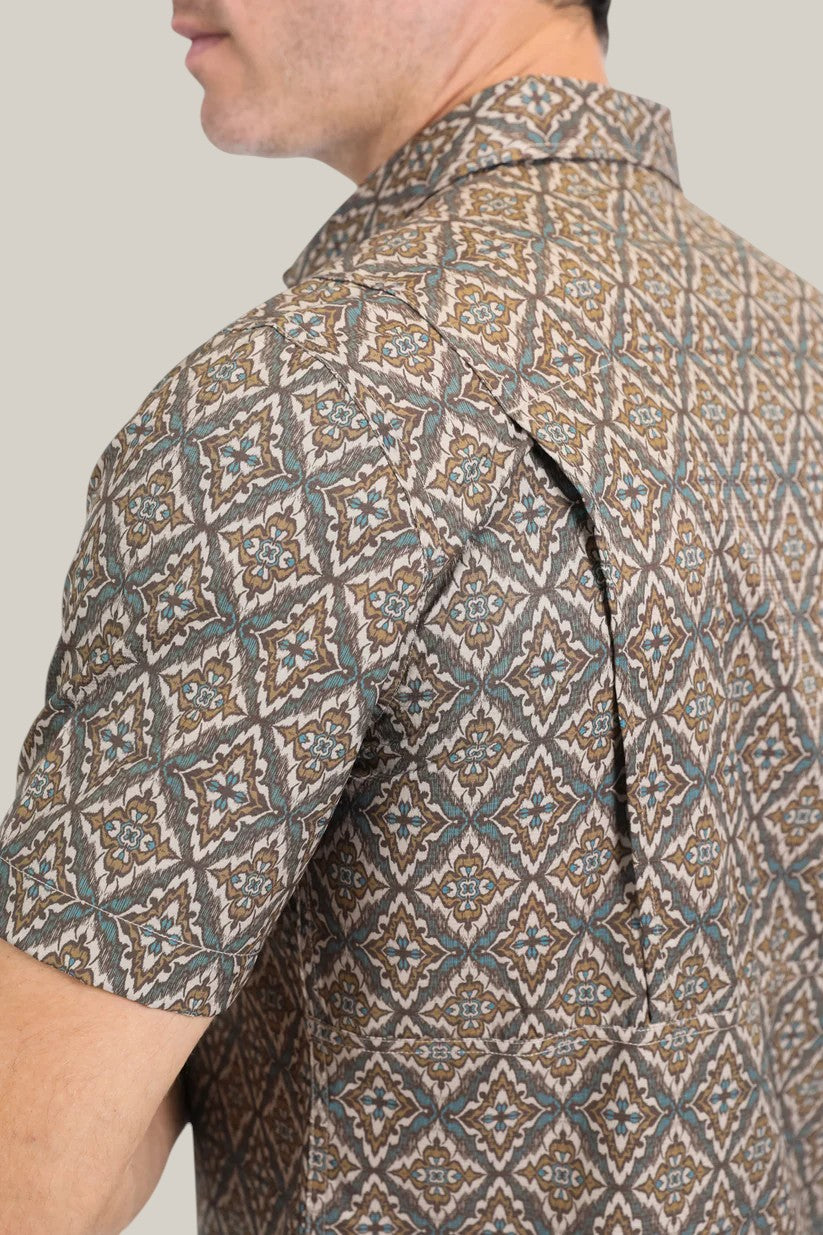 A person models the Mens Performance Western Short Sleeve Aztec Print Brown Shirt (PGW10638) against a plain background, highlighting its intricate design and collar in harmonious shades of brown, blue, and white.