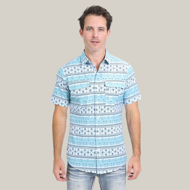 A person stands against a plain background wearing the Mens Performance Western Short Sleeve Aztec Print White Shirt (PGS10627), featuring horizontal blue and white geometric patterns.