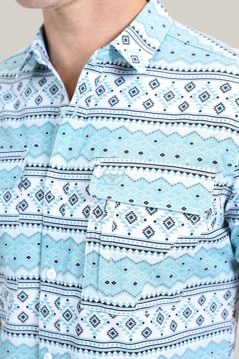 A close-up of a person wearing the Mens Performance Western Short Sleeve Aztec Print White Shirt (PGS10627) with geometric designs. This shirt features buttoned pockets and is partially buttoned up, revealing just the torso against a plain light background.