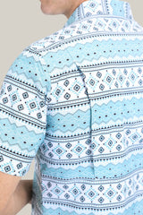 A person is wearing the Mens Performance Western Short Sleeve Aztec Print White Shirt (PGS10627), featuring a geometric diamond, zigzag, and horizontal line pattern in white, light blue, and dark blue. Theyre slightly turned away.