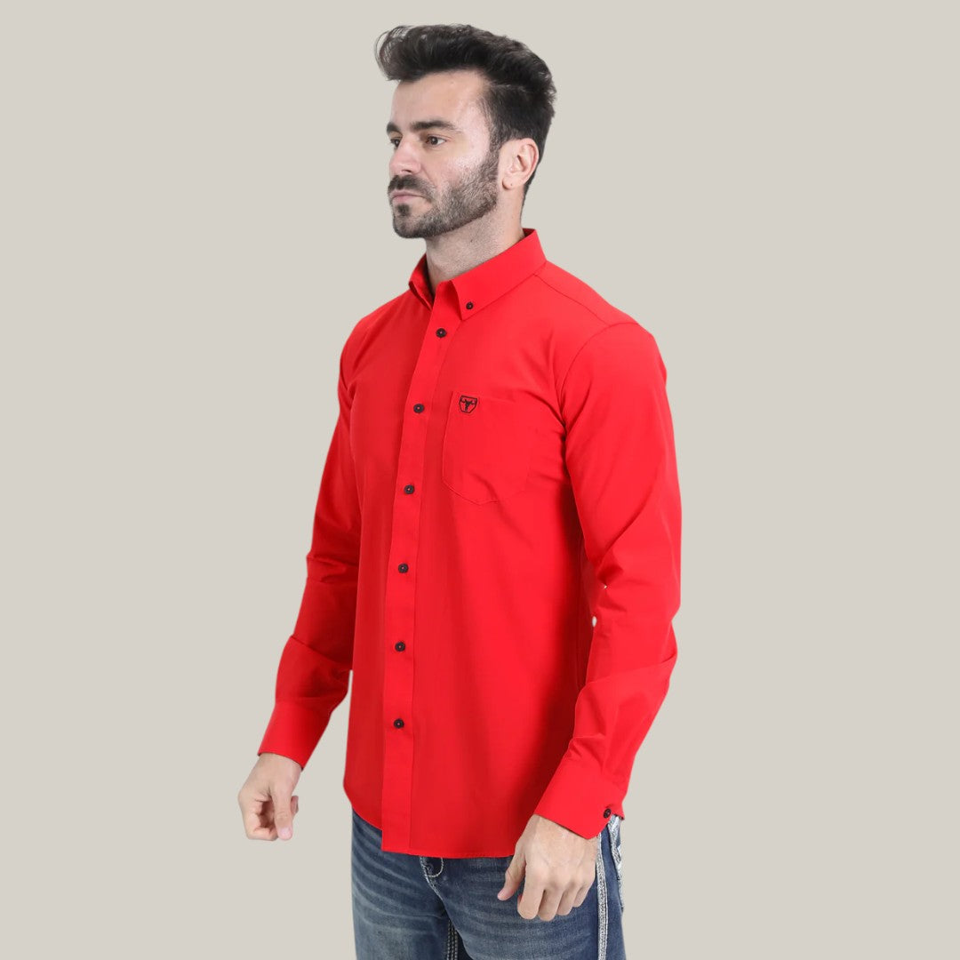 A man stands looking to the side, wearing the CTL10700 Mens Single Pocket Logo Modern Fit Stretch Dress Shirt in bright red with dark buttons. His hands hang by his jeans, emphasizing the sleek design that contrasts perfectly with a plain light grey backdrop.